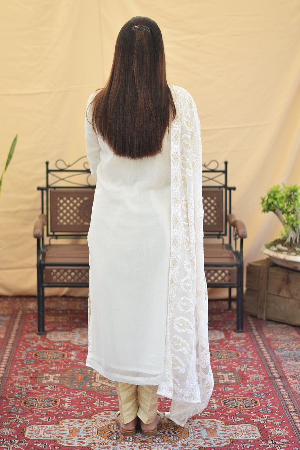 A woman's back in a simple white kurta, highlighting the elegant drape of the georgette fabric.