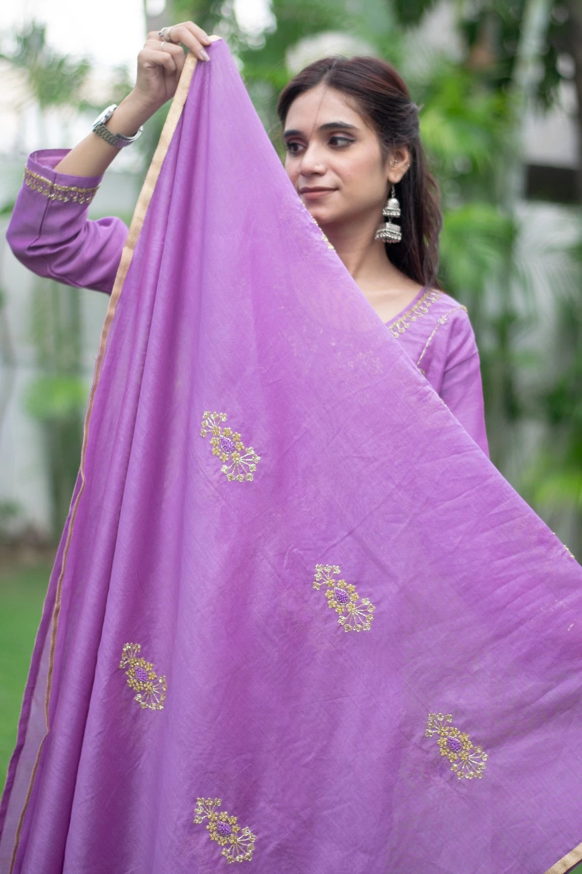 The subject of this image is a woman wearing a beautifully designed purple lilac kurta with loose-fitting trousers.
