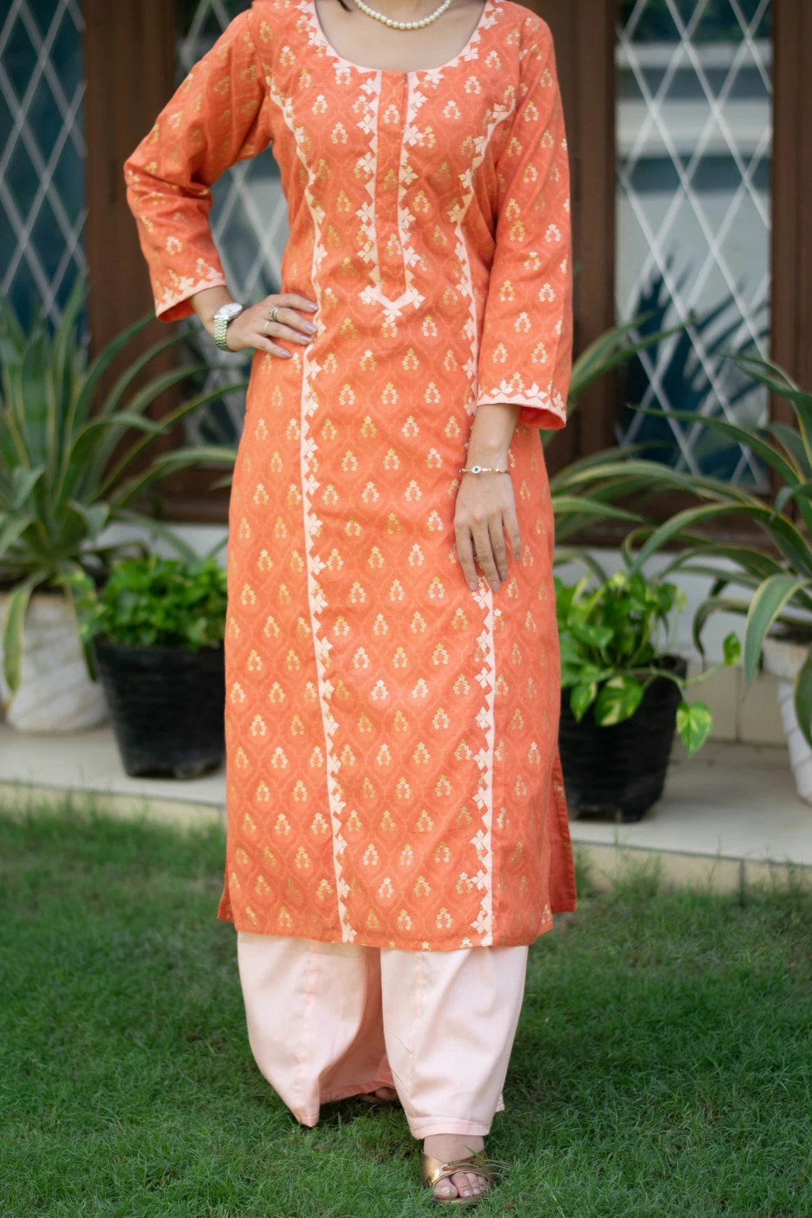 An image of a woman looking elegant in an orange silk kurta and trousers.