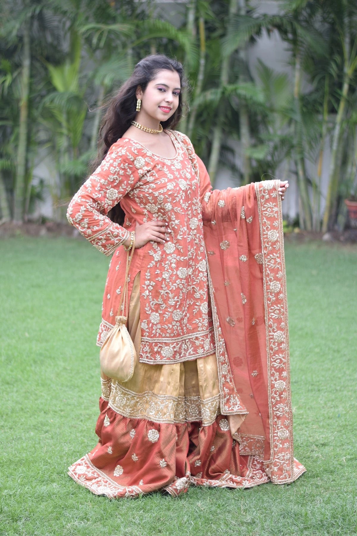A fashionable lady in a beautifully crafted farshi gharara in golden rust.