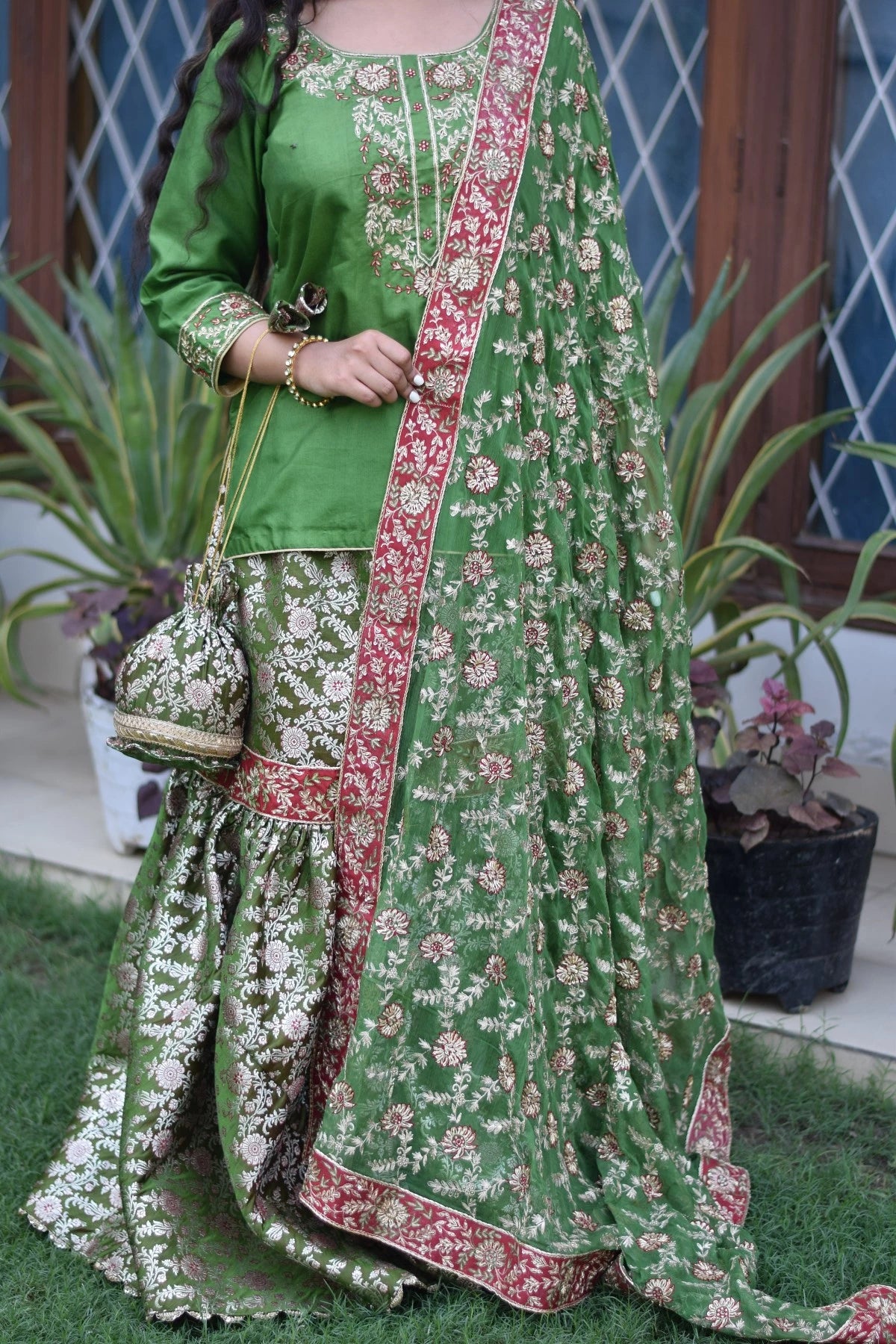 A beautiful bride wearing a green silk gharara suit with intricate kamkhab zardozi embroidery.