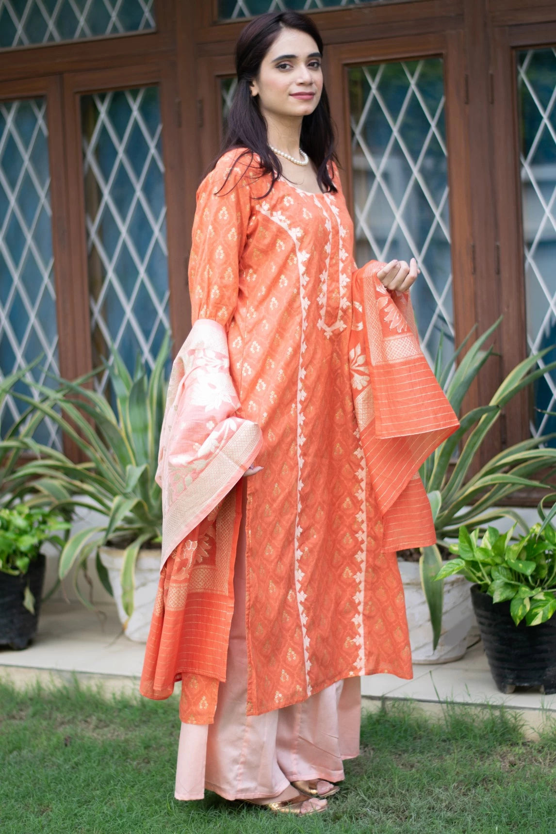 A traditional attire of an orange silk kurta and trousers worn by a woman