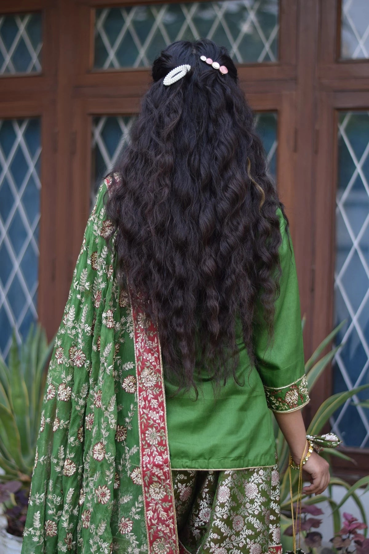 A traditional Indian wedding gharara suit made of green silk and adorned with kamkhab zardozi embroidery.