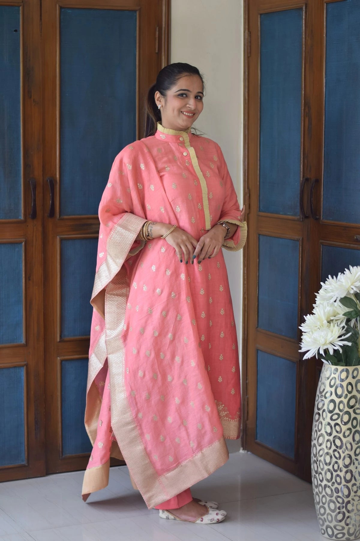 A woman wearing a peach linen kurta with a V-neckline and quarter sleeves.
