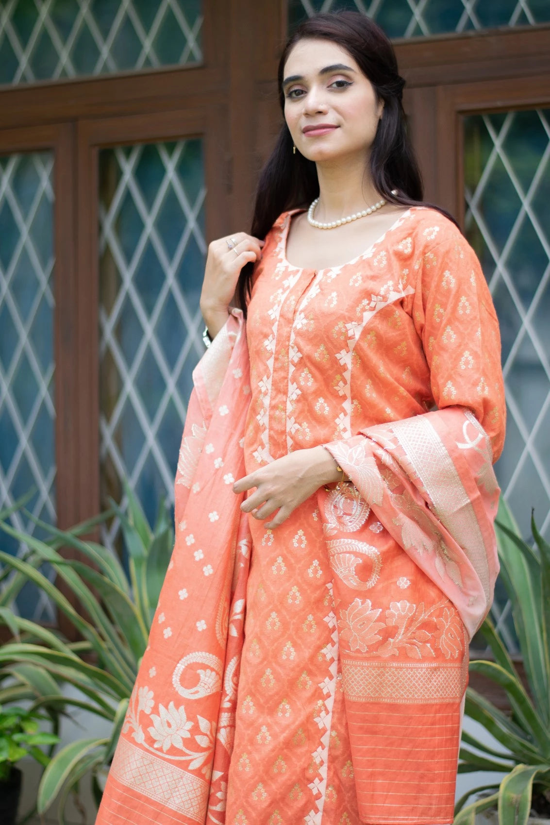 A female model wearing an orange silk kurta and matching trousers