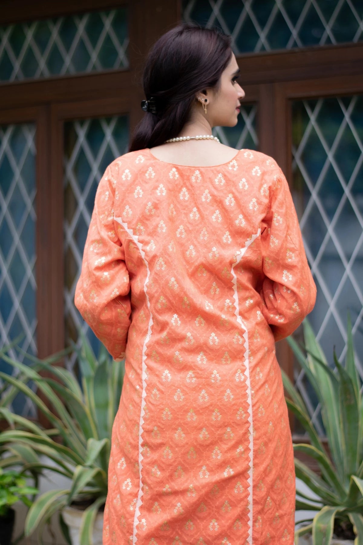 A stunning ethnic ensemble of an orange silk kurta and trousers worn by a woman