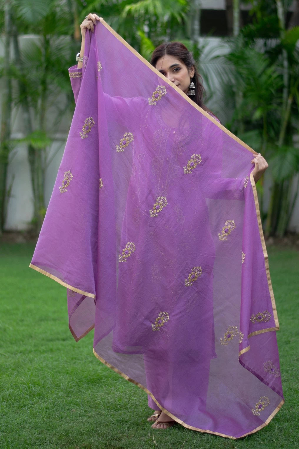 A woman stands tall in a purple lilac cut dana kurta with trousers in a well-lit room.