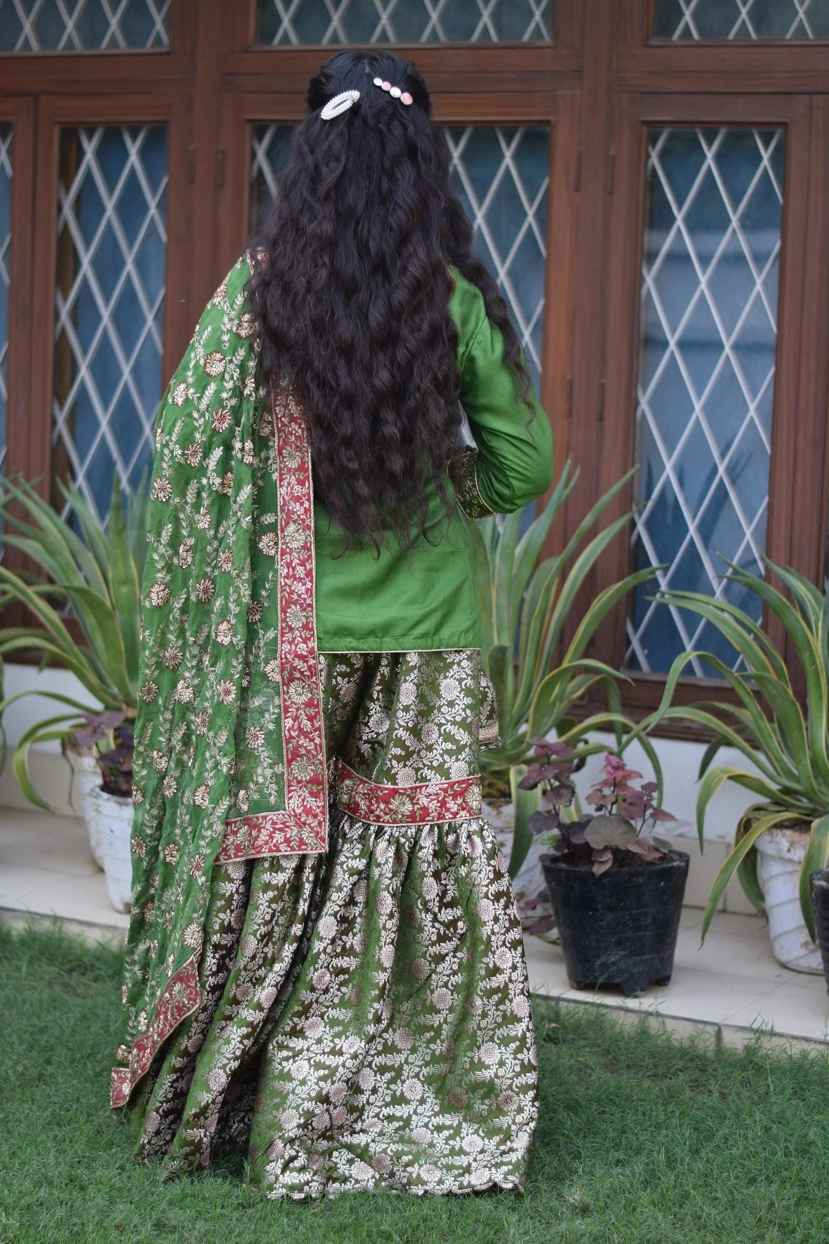 A green silk and kamkhab zardozi embroidered gharara suit worn by an Indian bride.