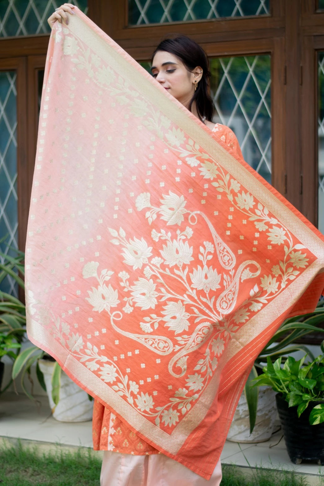 An image of a woman looking elegant in an orange silk kurta and trousers.