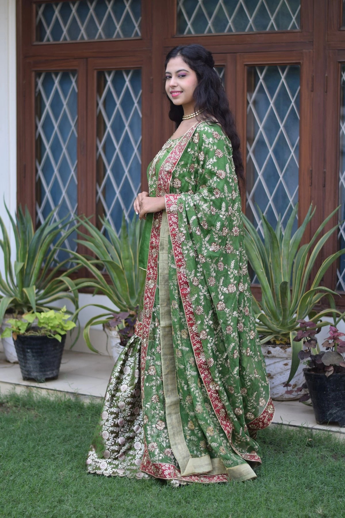 A beautiful Indian bride donning a green silk and kamkhab zardozi embroidered gharara suit.