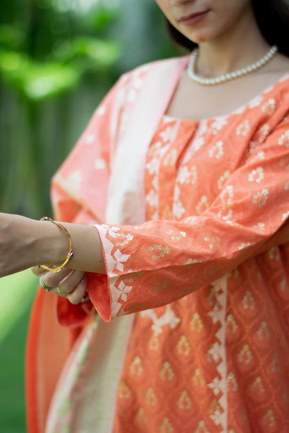 A stylish woman dressed in a vibrant orange silk kurta with trousers